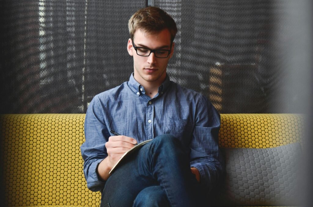 entrepreneur-startup-start-up-man-39866-39866 Person in Blue Denim Jacket Sitting on Chair While Writing